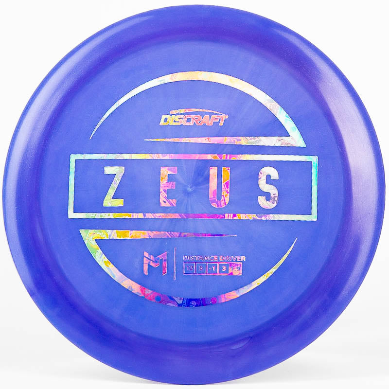 A purple colored Discraft Zeus distance driver on a white background